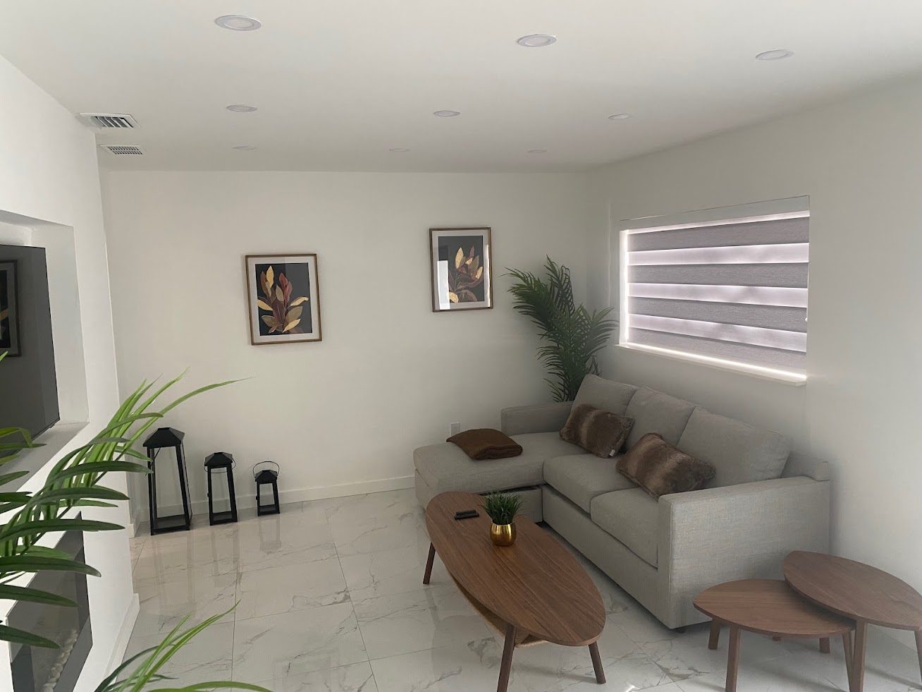 A modern living room with a grey sectional sofa and large marble floor tiles.