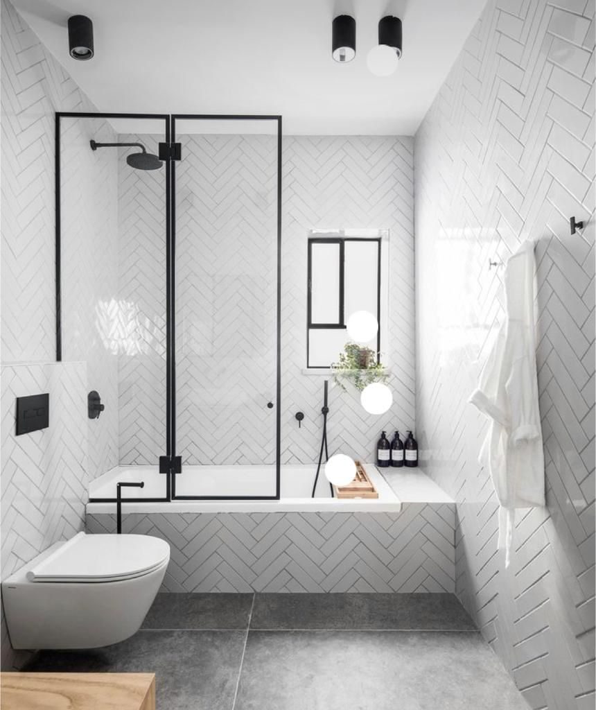 White herringbone tiled walls and matte black shower hardware in a modern bathroom.